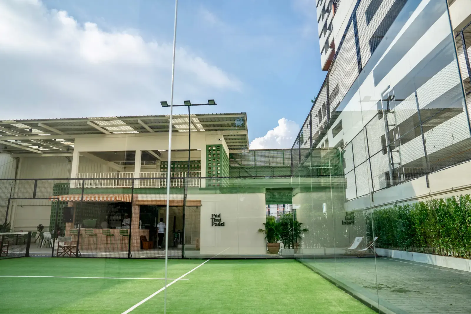 Outdoor padel court with clubhouse and city towers